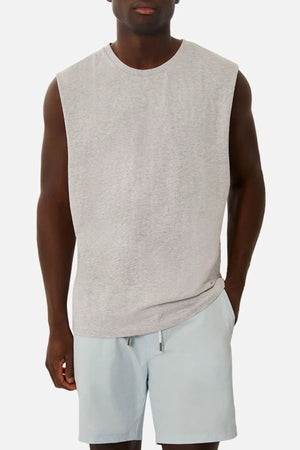 A person wears an Industrie The Triple G Sleeveless Tee in light gray with matching shorts against a plain white background. The relaxed fit complements their stance, left hand casually tucked into their pocket.
