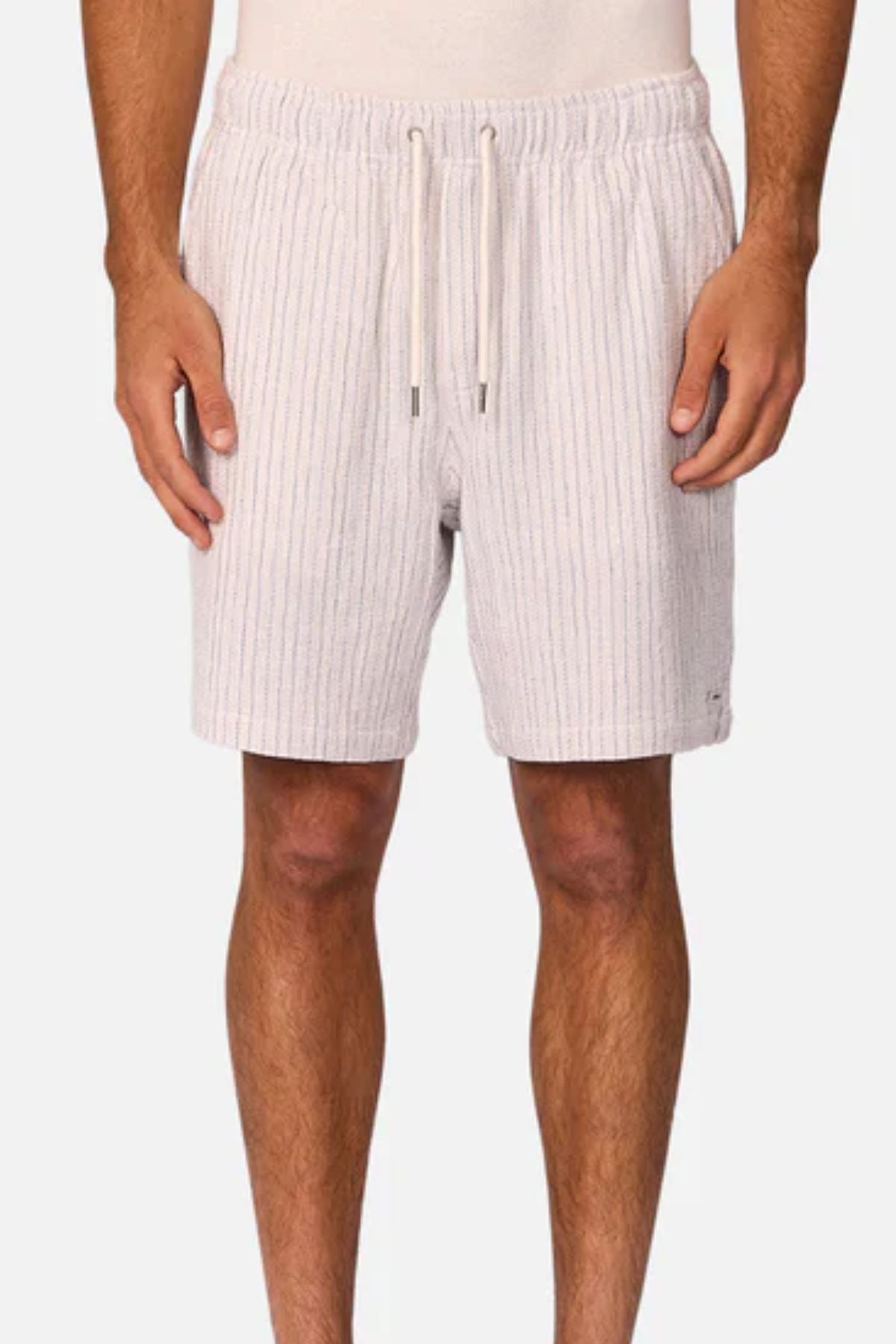 A person wears Industrie The Frescati Short—light-colored, knee-length linen shorts with vertical stripes and a drawstring waistband—standing against a plain, light background with hands relaxed at their sides.