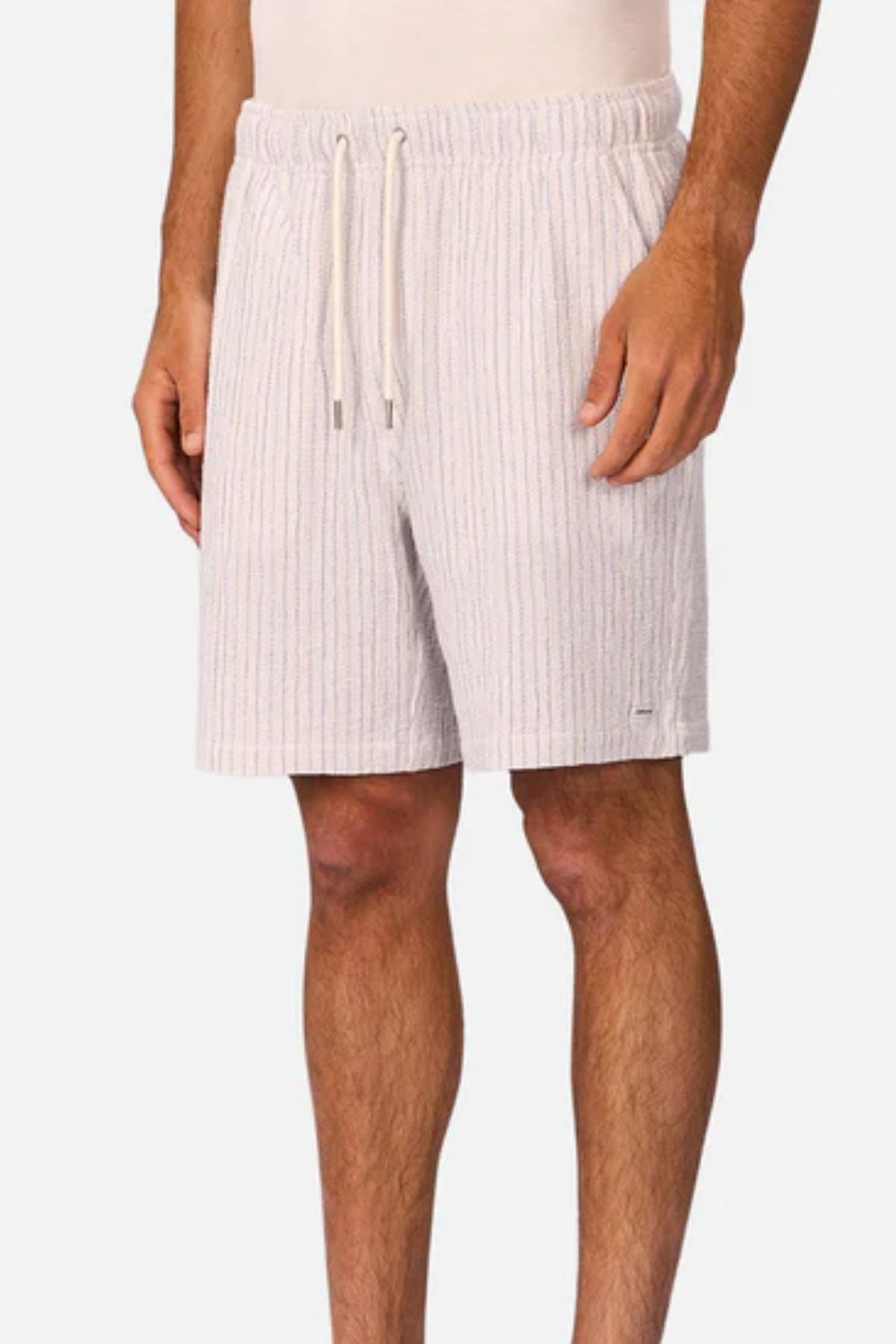 A person wears Industrie The Frescati Short—light-colored, knee-length men's summer shorts with subtle vertical stripes, side pockets, and a relaxed fit. Only the lower torso and legs are shown.