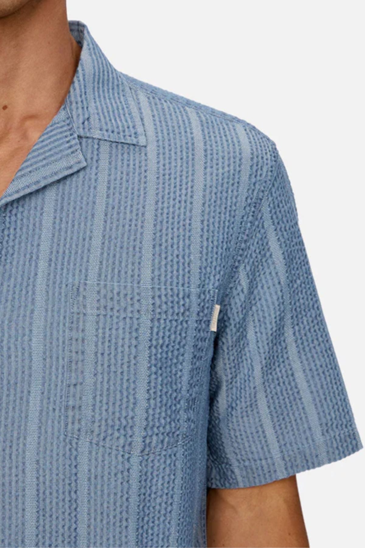 A person wearing the Industrie The Kimridge Short Sleeve Shirt in textured light blue, featuring a collar, shown from shoulders to mid-chest against a plain background.