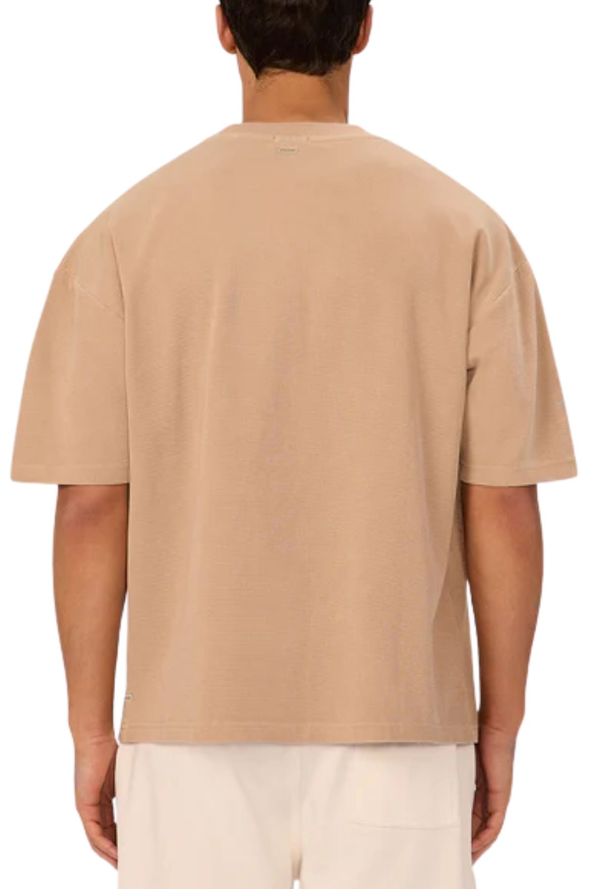 A person stands with their back to the camera wearing the Industrie The Marlon Tee in beige and white pants, ideal for casual wear. The background is plain white.
