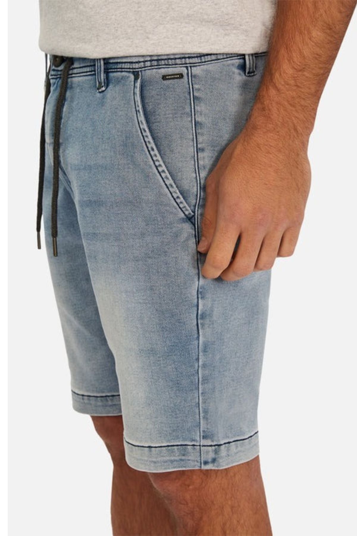 A person is shown from the waist down wearing the Industrie The Drifter Denim NC Short in light blue, featuring a black drawstring. These slim fit shorts include side pockets and a subtle worn texture, which are perfectly complemented by their cuffed hem. Paired with a light gray shirt, this outfit exudes casual style.