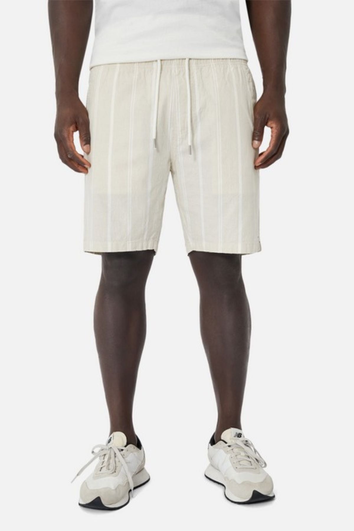 A person wearing a white t-shirt, Industrie The Bel Air Short featuring an elastic waistband, and white sneakers stands against a plain background.