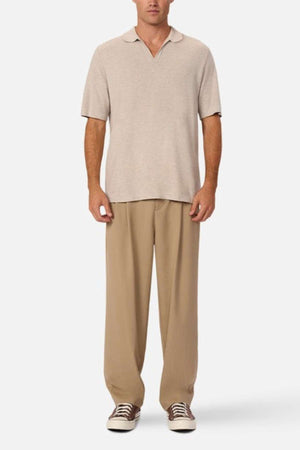 Industrie - The hampshire polo shirt - in colour beige marle - a warm light coloured polo shirt. A man modelling the shirt with brown trousers.