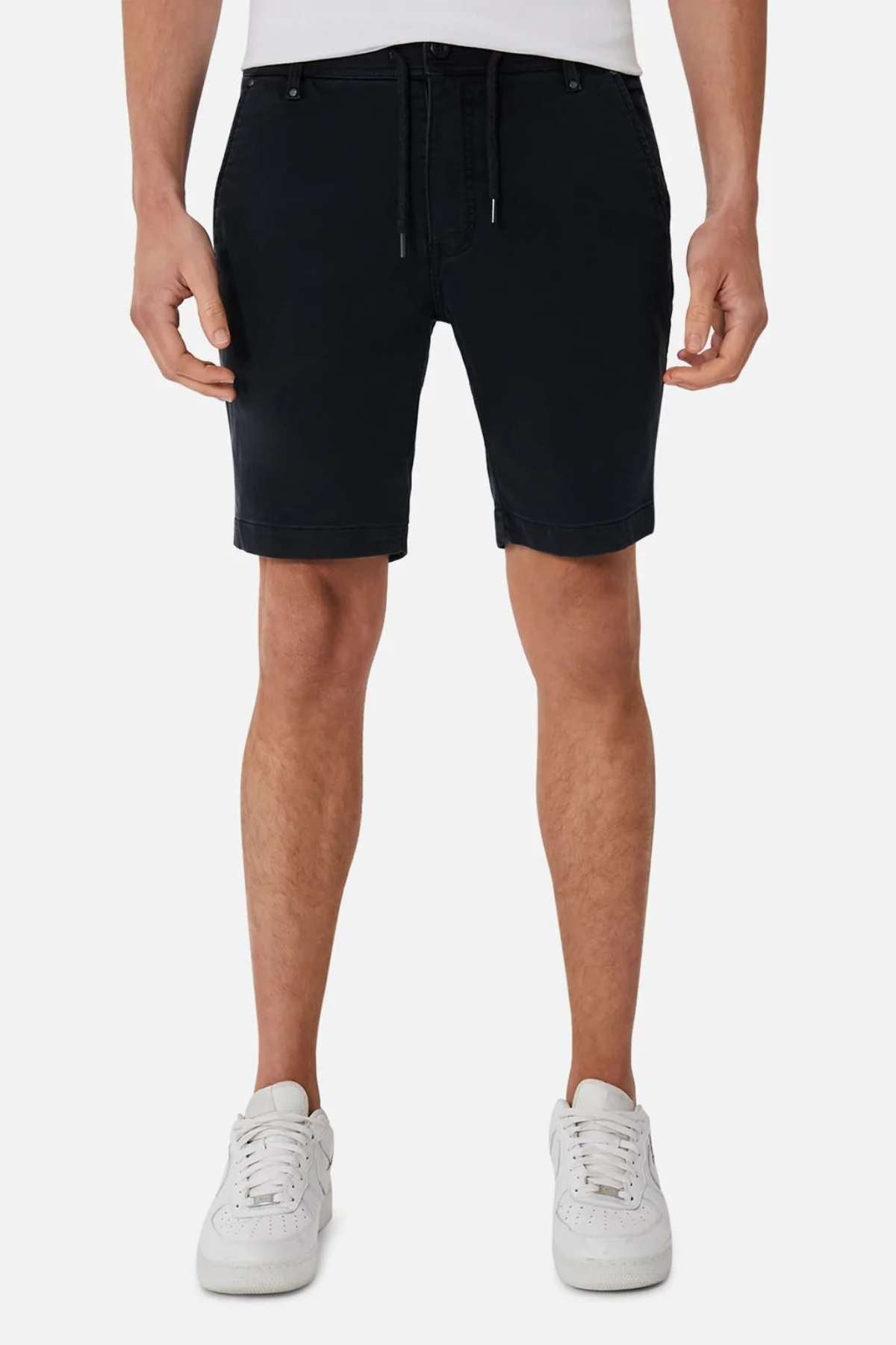 A person wearing Industrie The New Drifter Cuba Shorts and white sneakers stands against a plain white background. The shorts feature a comfortable belt-loop waist, with the person's hands hanging by their sides. Only the lower half of the body is visible.