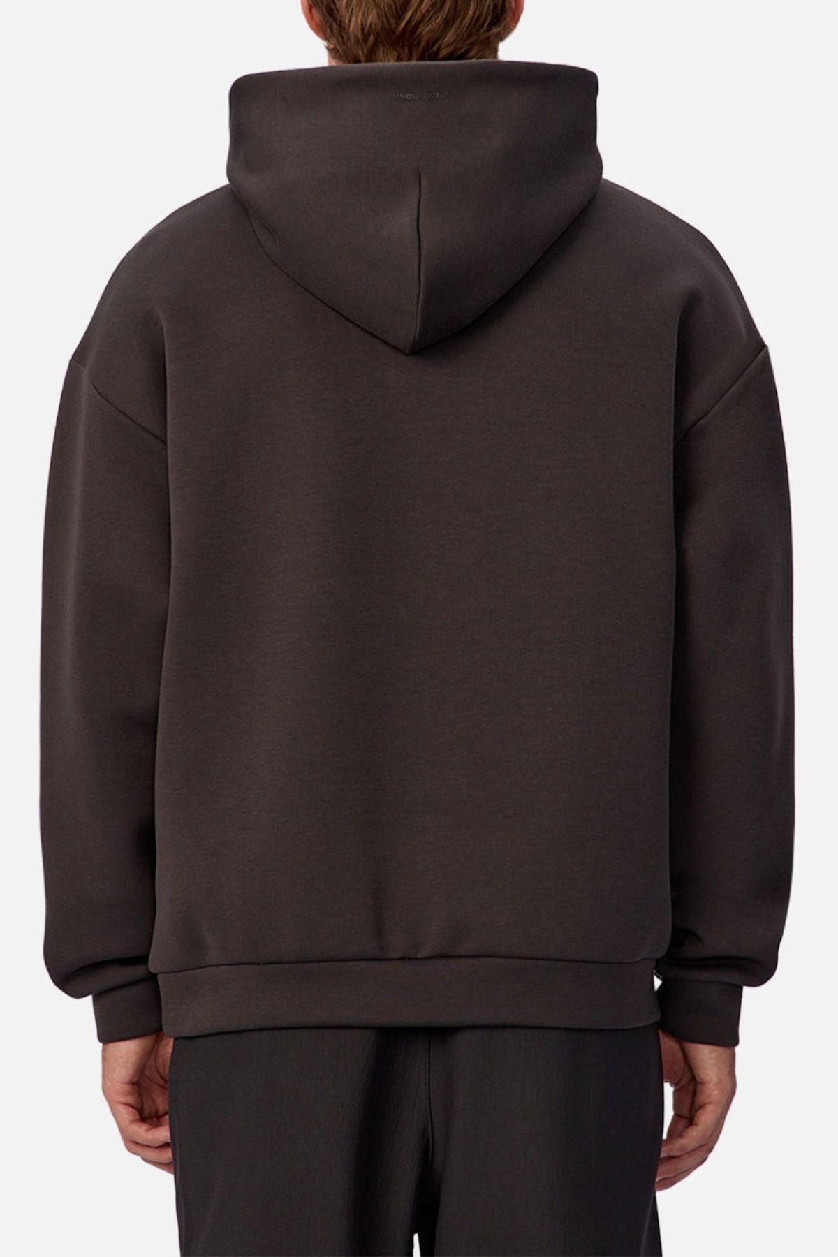 Someone is seen from the back wearing the Industrie The Tech Del Sur Hoodie, a loose-fitting, dark gray pullover with the hood up, against a plain light background.