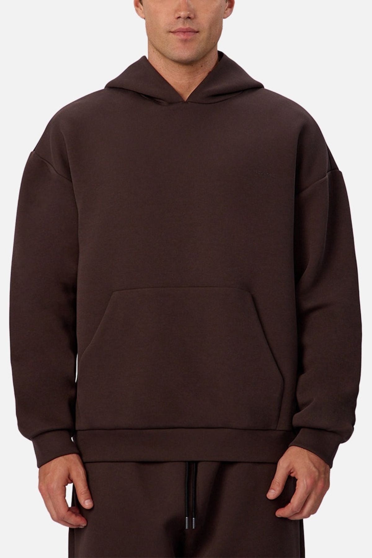 Someone is wearing the Industrie The Tech Del Sur Hoodie in dark brown, featuring a loose fit, breathable fabric, front pocket, and matching drawstring pants, standing against a plain light background.