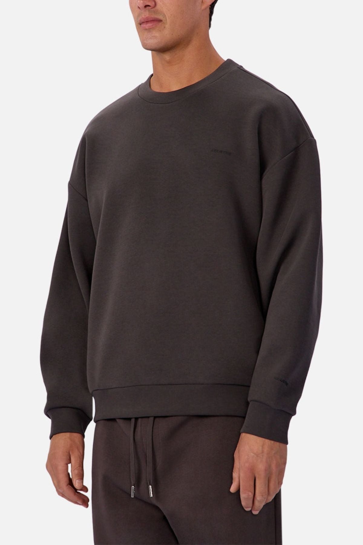 A man wears the Industrie The Tech Del Sur Sweat and matching sweatpants in dark gray against a light background. With its minimalist design and athletic construction, itβs ideal for an active lifestyle.