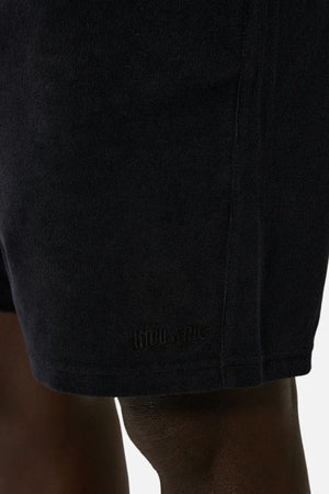 Close-up image of a person's upper legs wearing the Industrie The Wynwood Short, crafted for an ideal summer style. The black men's shorts display understated branding near the hem, set against a neutral background.