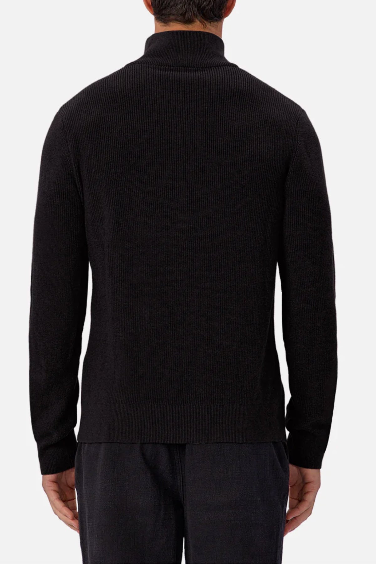 A person is shown from the back wearing the Industrie The New England Zip Neck Knit, a black long-sleeve sweater with a high collar, paired with dark pants against a plain white background.