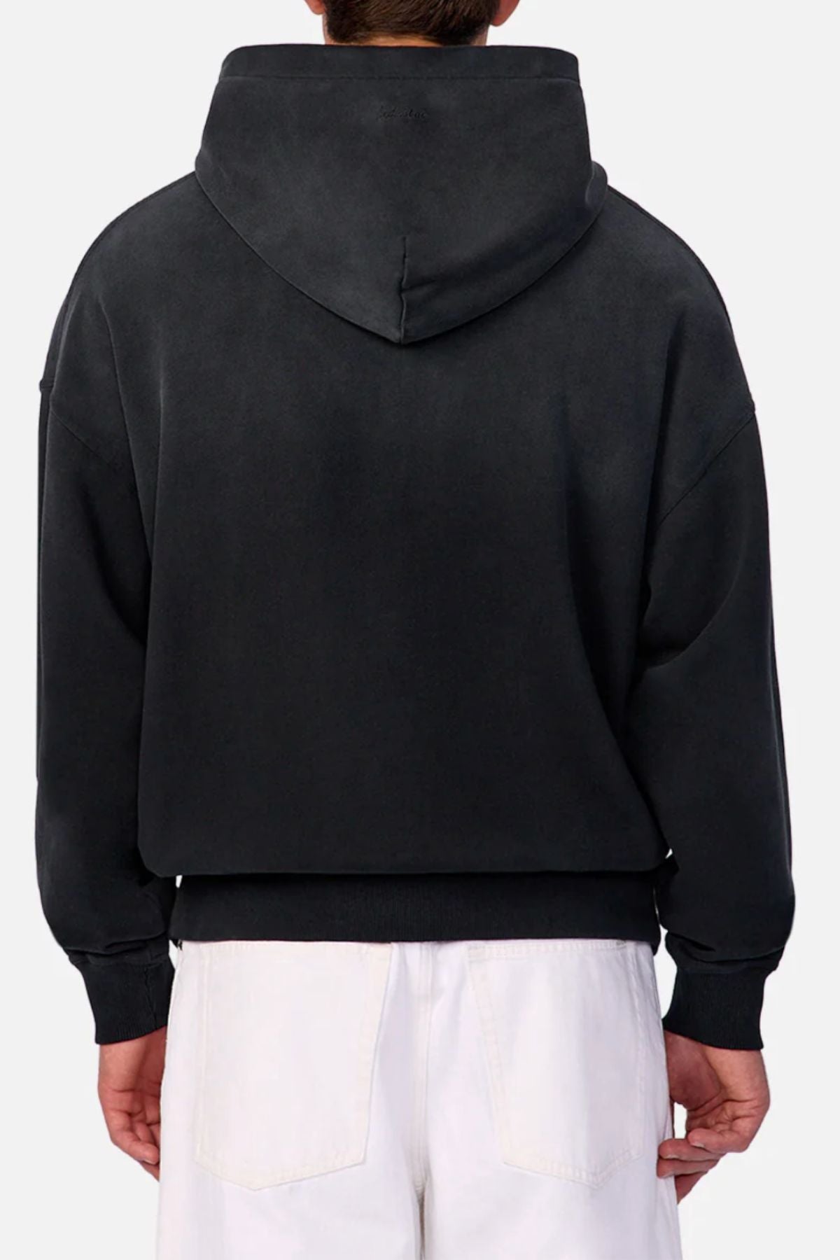 Someone wears the Industrie The Sandblast Hoodie in black with the hood down, viewed from behind. They style it with white pants for a relaxed look against a light, plain background.