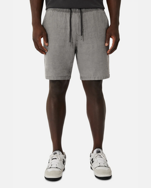 A man, only his lower half visible against a white backdrop, wears relaxed-fit gray drawstring shorts, a black shirt, and white sneakers, highlighting the casual elegance of the Industrie The Marina Linen Short in luxurious 100% linen.