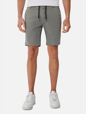 A person wearing Industrie The New Drifter Cuba Short—modern slim fit, grey knee-length smart casual shorts with a black drawstring—paired with a white shirt and white sneakers, stands against a plain white background.