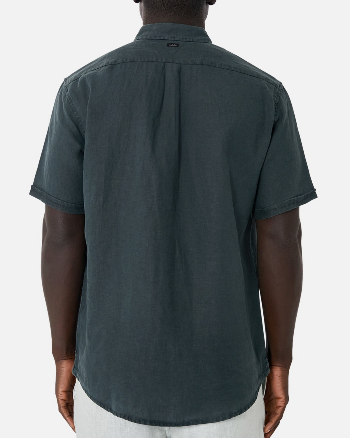 Someone seen from behind wears the Industrie The Tennyson Linen Short Sleeve Shirt in dark linen with light-colored pants, standing against a plain white background.