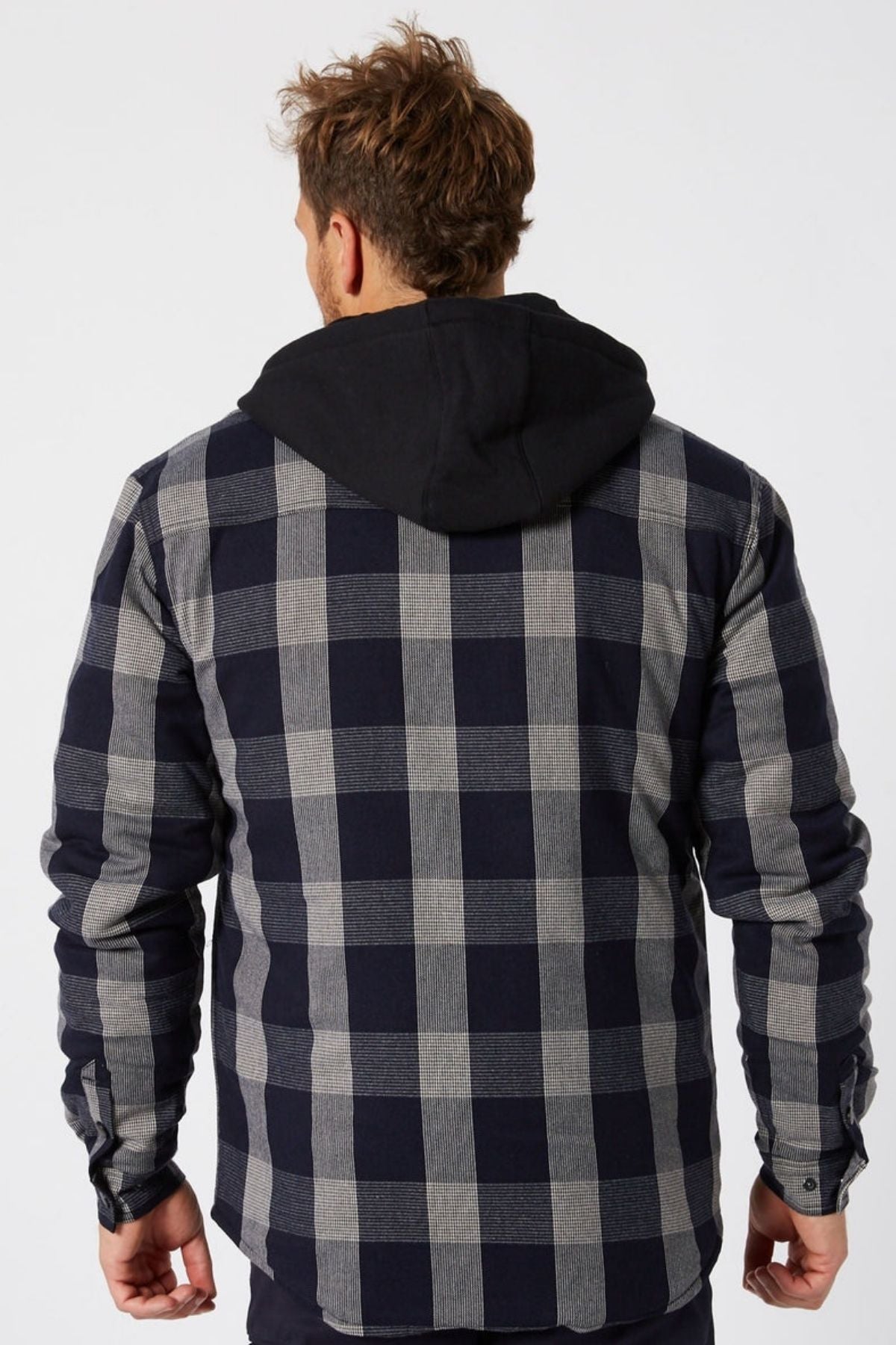 A man with short, messy brown hair faces away from the camera, wearing a Jetpilot Quilted Flannel Jacket over a black hooded sweatshirt.