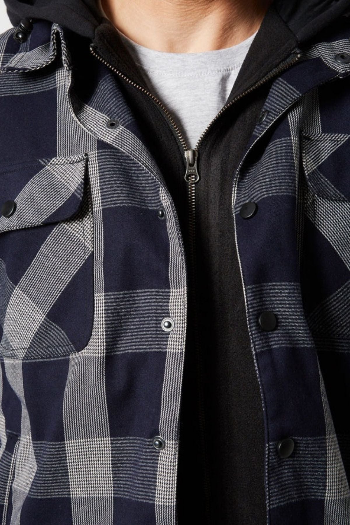 Close-up of a person wearing a Jetpilot Quilted Flannel Jacket in blue and white over a black zip-up hoodie and light gray t-shirt, with the jacket partially unbuttoned to reveal the cozy layers underneath.