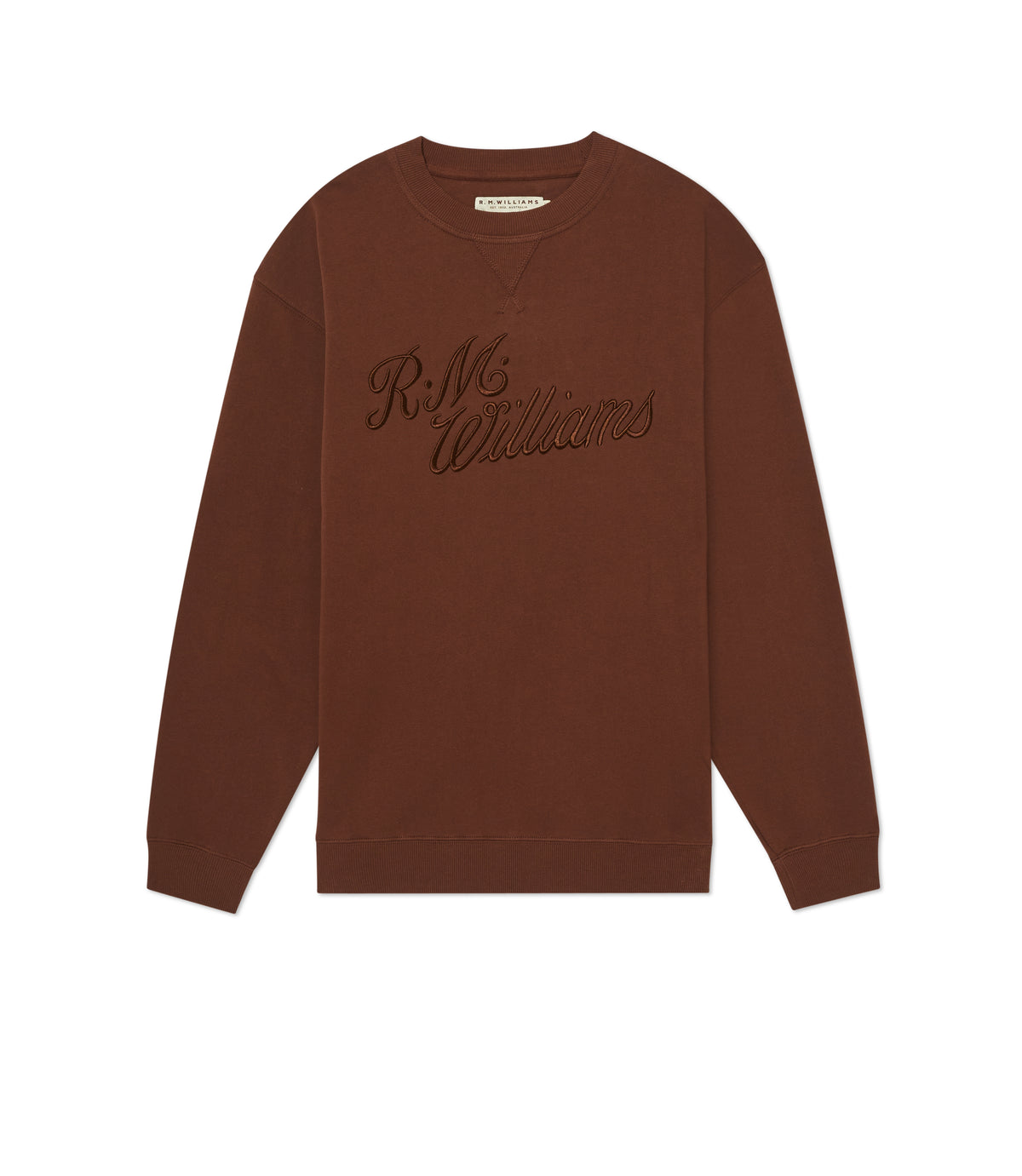 The RM Williams R.M.W Script Crew Neck is a brown cotton blend jumper with long sleeves, ribbed cuffs, and cursive R.M.Williams embroidery on the chest, shown laid flat on a white background.