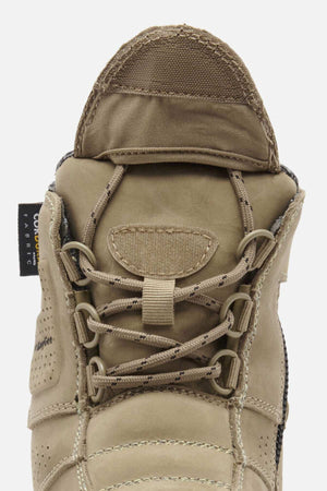 A close-up of the tan King Gee Bennu Pro 6 Work Boot highlights its laces, tongue, side fabric tag, and slip-resistant outsole as the boot faces upward.