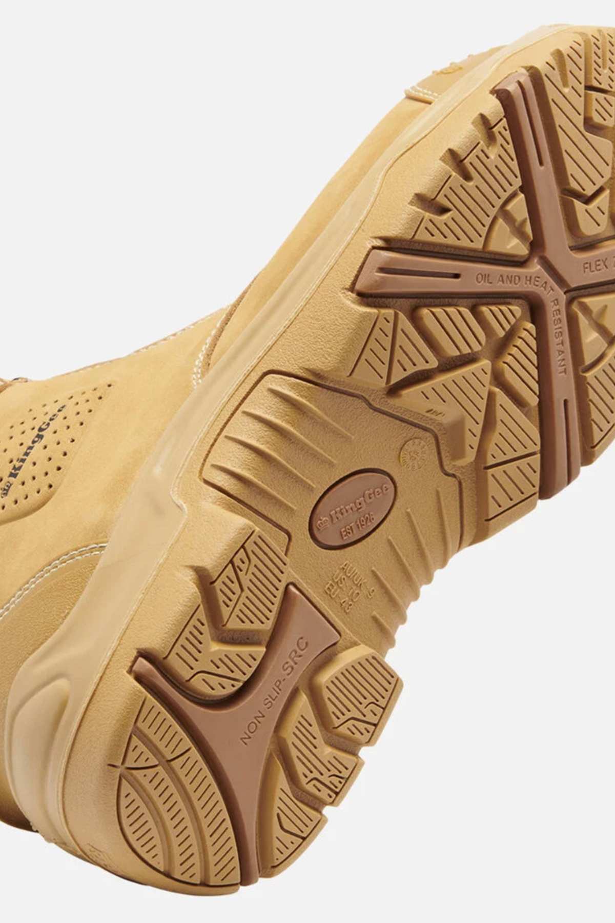A close-up of the tan King Gee Bennu Pro 9 Work Boot's sole reveals a rugged, textured tread with slip-resistant properties and symbols such as a large "X" for flexibility. The boot features a steel toe, suggesting durability and suitability for tough conditions.