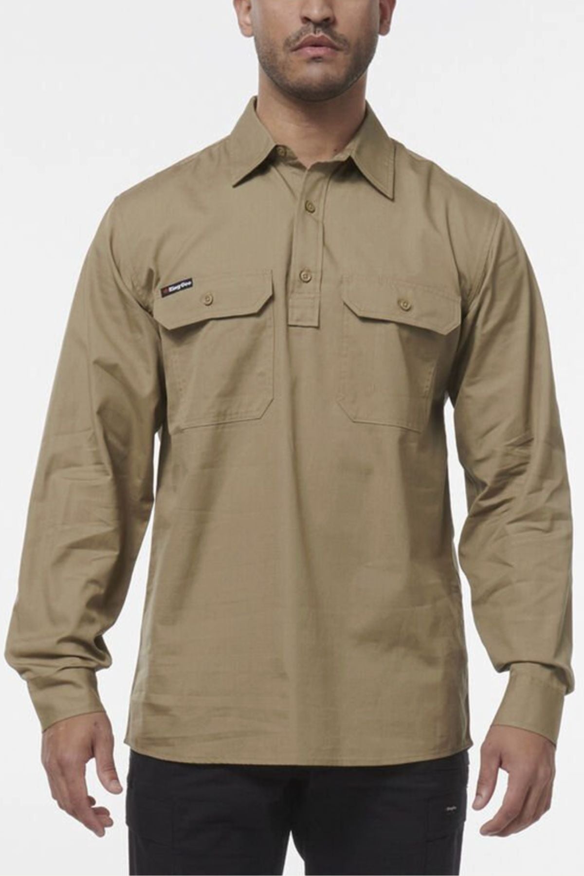 A man stands against a plain white background wearing a khaki King Gee Workcool Vented Closed Front Shirt with long sleeves and two front chest pockets.