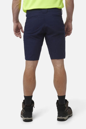 A person is seen from the back wearing King Gee Workcool Pro Shorts, black socks, brown work boots, and a fluorescent yellow shirt against a plain white background.