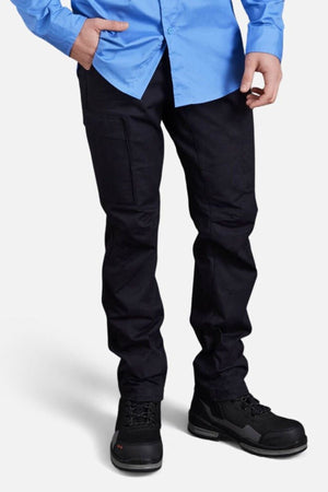 A person stands against a plain white background, cropped at the shoulders, wearing a bright blue button-up shirt, black King Gee Workcool Pro Stretch Cargo Pants with multifunctional pockets, and black work shoes.
