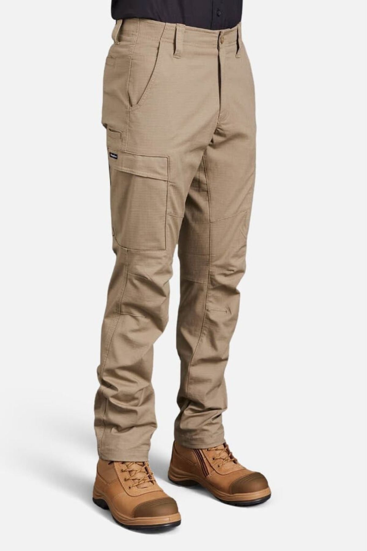 A person wearing King Gee Workcool Pro Stretch Cargo Pant in tan, made from stretch ripstop fabric with multiple pockets, paired with brown work boots, stands against a plain white background. Only the lower body is shown.