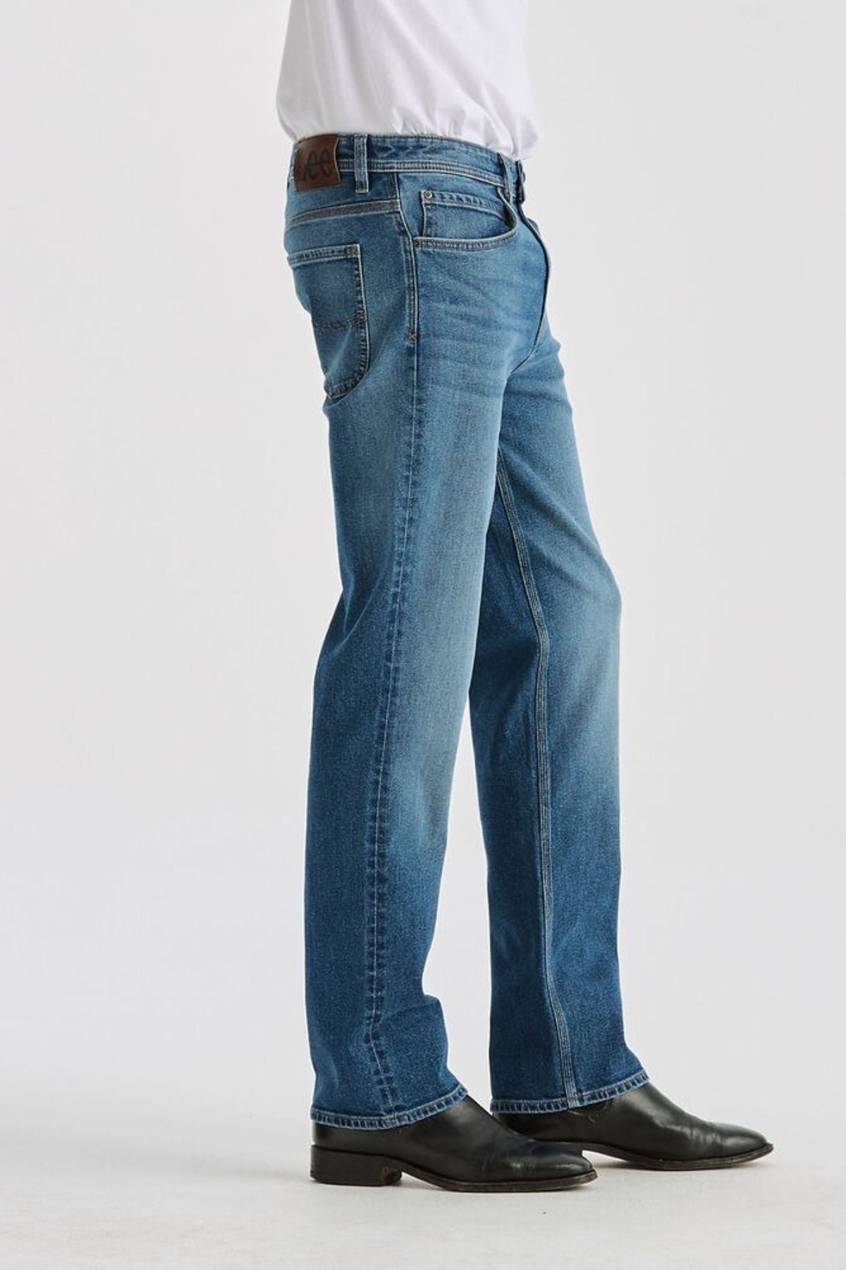 Wearing Lee Originals L101 Straight Jean in light blue, a white tucked-in shirt, and black leather shoes, a person stands against a plain white background with only the lower half of the body visible.