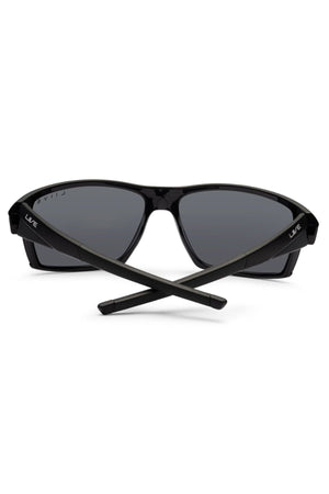 The Liive X Ignite X Sunglasses feature a black, sporty wrap-style frame with dark lenses and crossed arms, offering a sleek, modern silhouette and contemporary appeal.