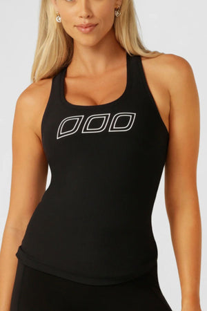 A woman with long blonde hair wears the Lorna Jane Amy Fitted Active Rib Tank, a black racerback style featuring three white-outlined geometric shapes on the chest. She stands facing forward against a plain light background.