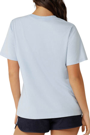 A woman with long brown hair is seen from the back wearing the Lorna Jane Athletic Club Relaxed T-Shirt in light blue and dark shorts against a plain white background.
