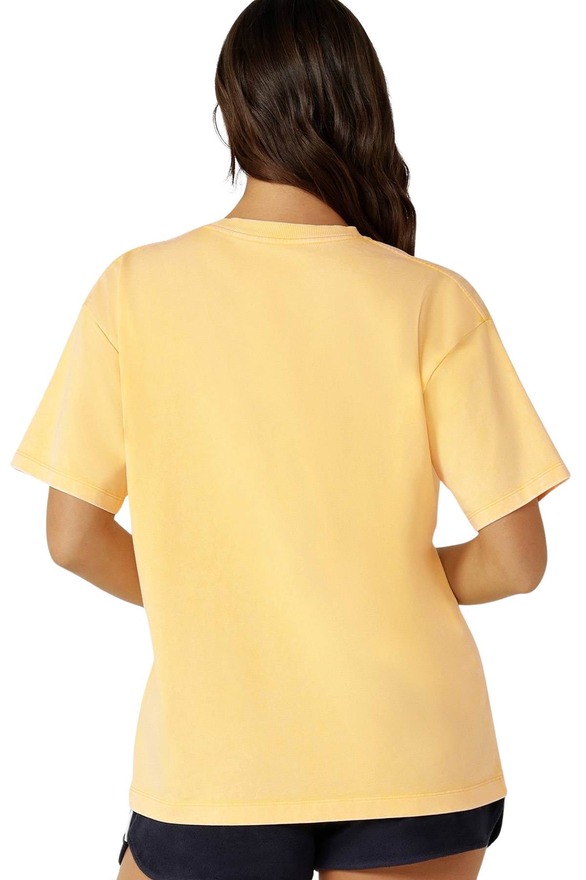 A person with long brown hair, shown from the back against a white background, wears a loose-fitting Lorna Jane Classics Washed Vintage T-Shirt with short sleeves and dark shorts.