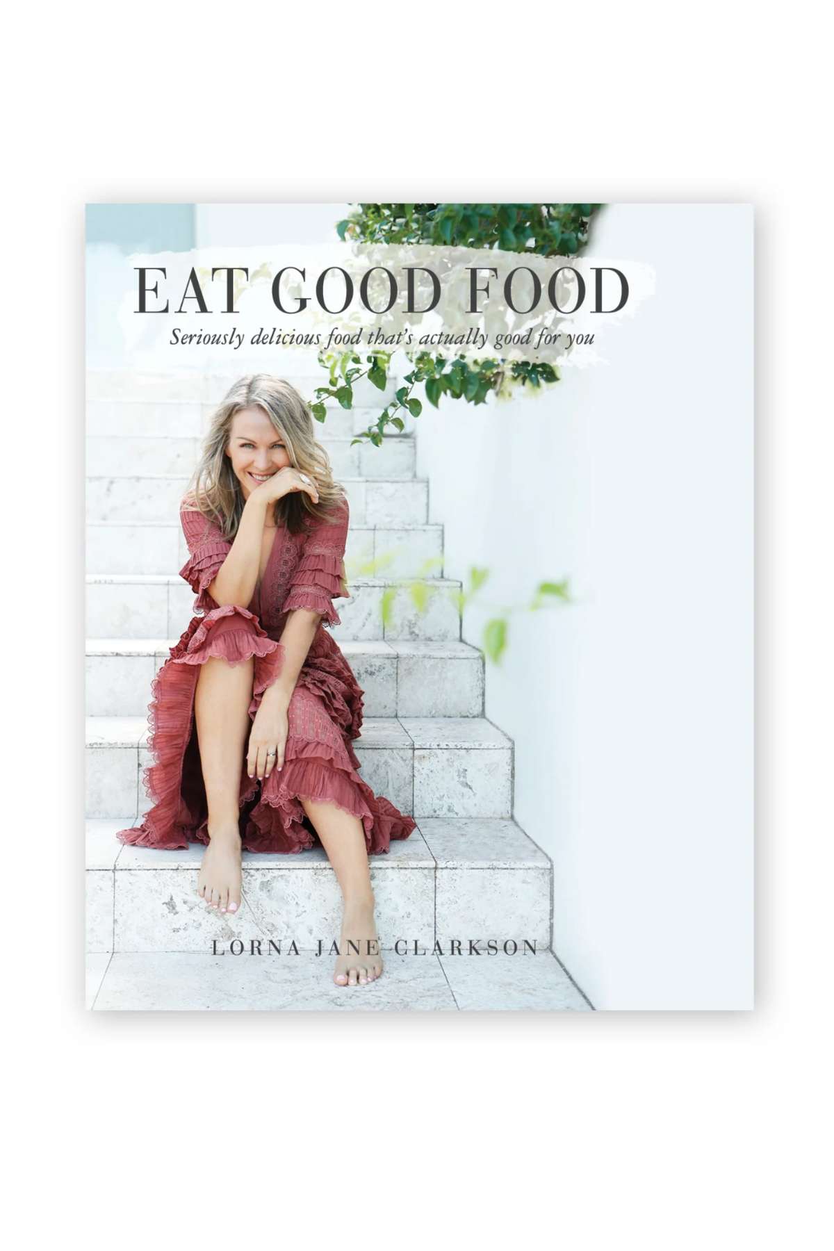 Cover of "Lorna Jane Eat Good Food" features a smiling woman in a pink dress, barefoot on white steps with greenery behind her, embodying the book’s focus on nutritious and delicious healthy choices.
