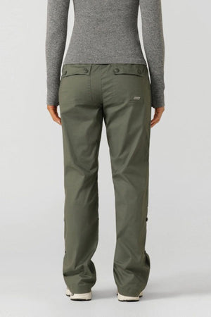 A person stands with their back to the camera, wearing olive green Lorna Jane Flashdance Pant with an adjustable waist and a fitted gray long-sleeve top, set against a plain light background.