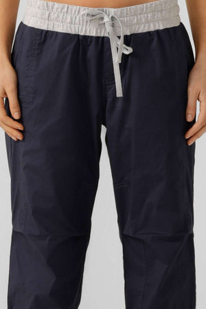 A person wears Lorna Jane Flashdance Pant in navy blue, with a light gray waistband and winter fabrication, shown from waist to mid-thigh, hands relaxed at their sides.