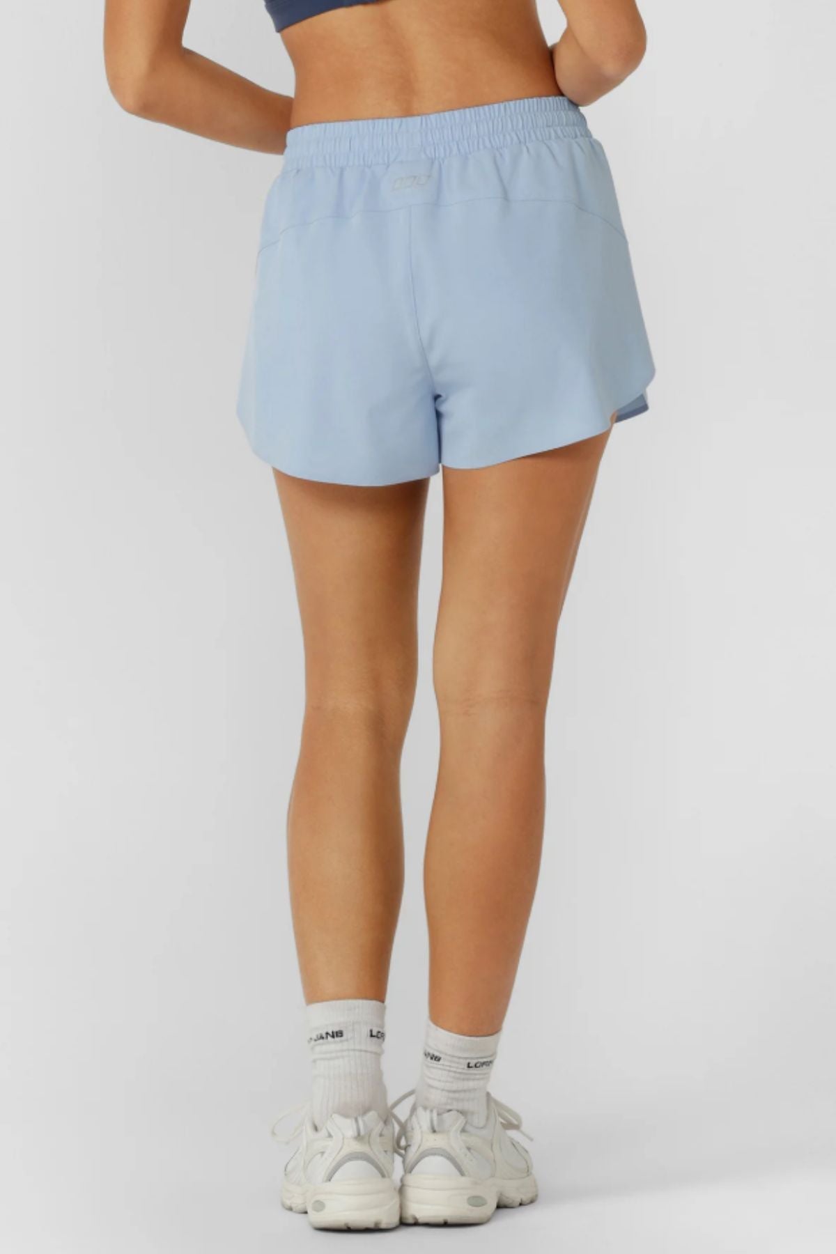 A person's legs and Lorna Jane Lightspeed Phone Pocket Run Short, designed with sweat-wicking fabric for comfort and style.