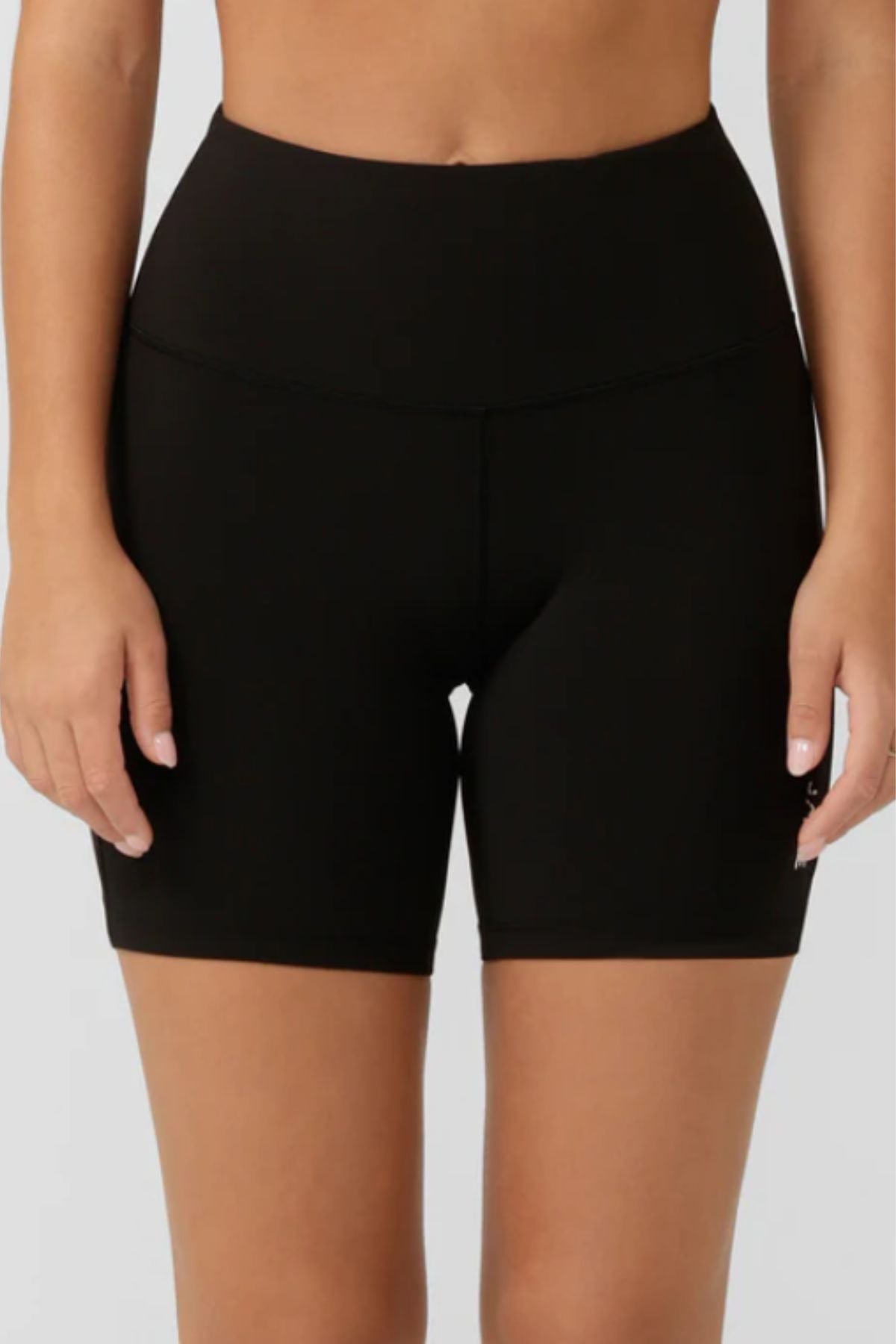 A person wears Lorna Jane Lotus No Chafe Phone Pocket 12cm Bike Shorts in black, shown from waist to mid-thigh against a plain light background.