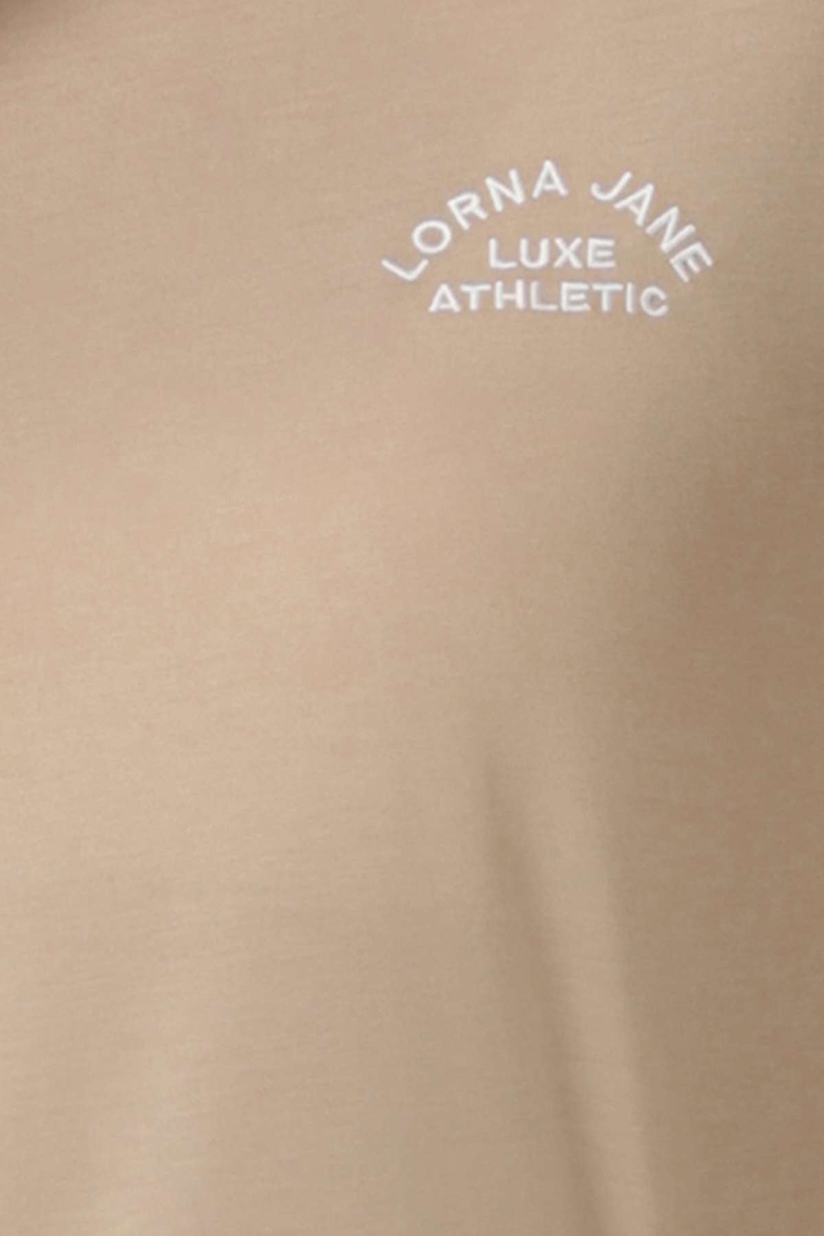 Close-up of the Lorna Jane Lotus T-Shirt’s beige fabric, showcasing its white embroidered "LORNA JANE LUXE ATHLETIC" logo arched to embody an active lifestyle.