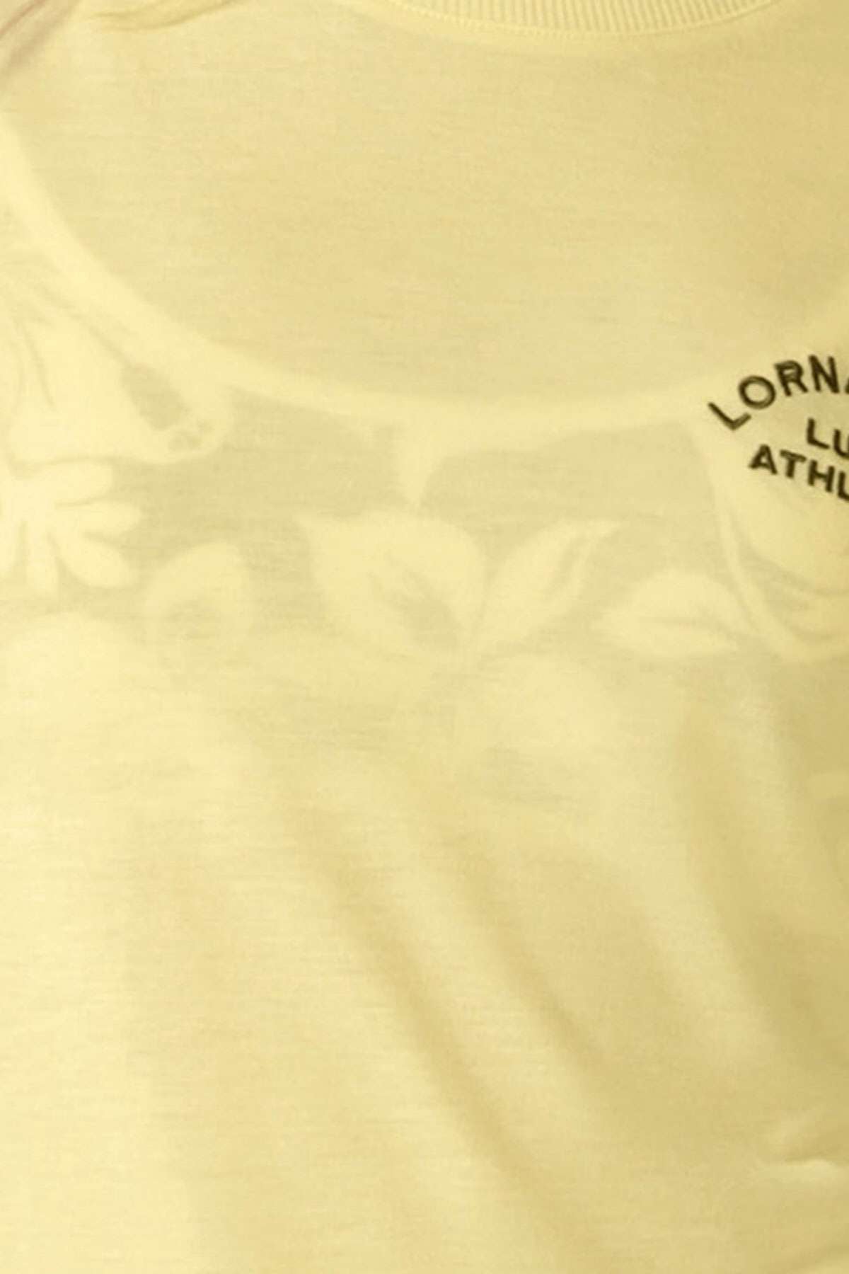 Close-up of a light yellow Lorna Jane Lotus T-Shirt with a subtle floral pattern and a small, partially visible "LORNA JANE ATHLETIC" logo in black on the upper right side—ideal for an active lifestyle.