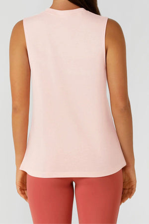 A person is seen from the back wearing a sleeveless, light pink Lorna Jane Lotus Muscle Tank with high-waisted, rose leggings against a plain light gray background.