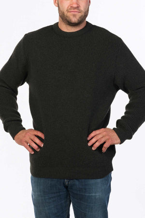A person stands confidently with their hands on their hips, wearing the MKM Original Backyard Knit crafted in New Zealand and blue jeans. The plain white background highlights the casual wear ensemble.