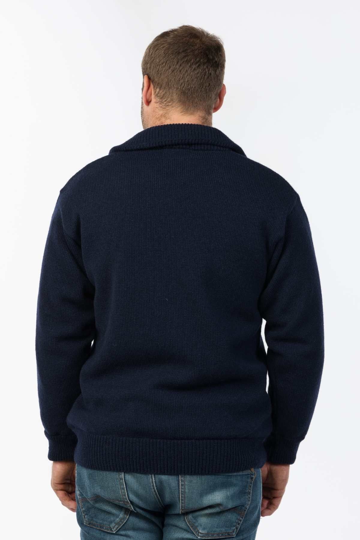 A person wearing a navy MKM Windbreaker Knit jumper, crafted in New Zealand from 100% wool, stands with their back to the camera against a plain white background.