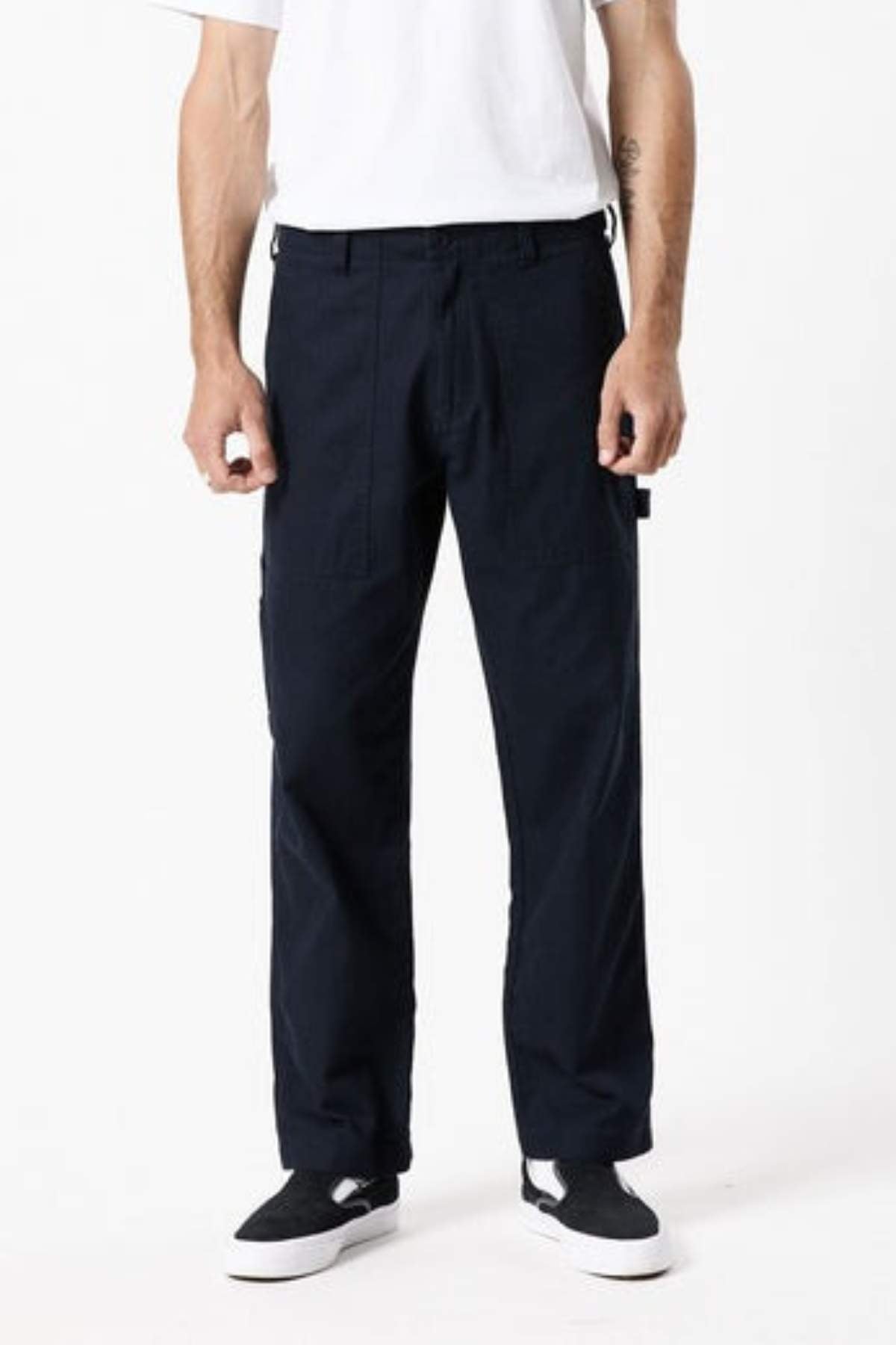 A person wears black Mr Simple Carpenter Pant, a white t-shirt, and black-and-white sneakers, standing facing forward against a plain white background. The image is cropped from the shoulders down.
