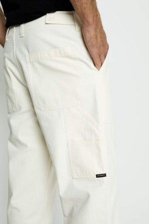 A person models the Mr Simple Carpenter Pant in a relaxed fit, off-white style with their right hand in the pocket. Only the lower torso and upper legs appear against a plain light background.