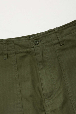 Close-up of the waistband and upper section of the Mr Simple Carpenter Pant in olive green, showing a button closure, belt loops, stitching details, and a workwear-inspired look crafted from 100% cotton on a plain background.