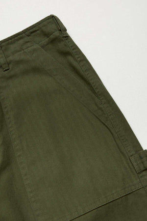 Close-up of Mr Simple Carpenter Pant in olive green, featuring the waistband, belt loop, and side pocket. The workwear-inspired design showcases textured 100% cotton fabric and detailed stitching against a plain light background.