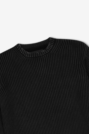 The Mr Simple Fisher Knit sweater, shown in black with a ribbed texture and round neckline, lies flat against a white background. Vertical ribs enhance its relaxed fit for a timeless style.