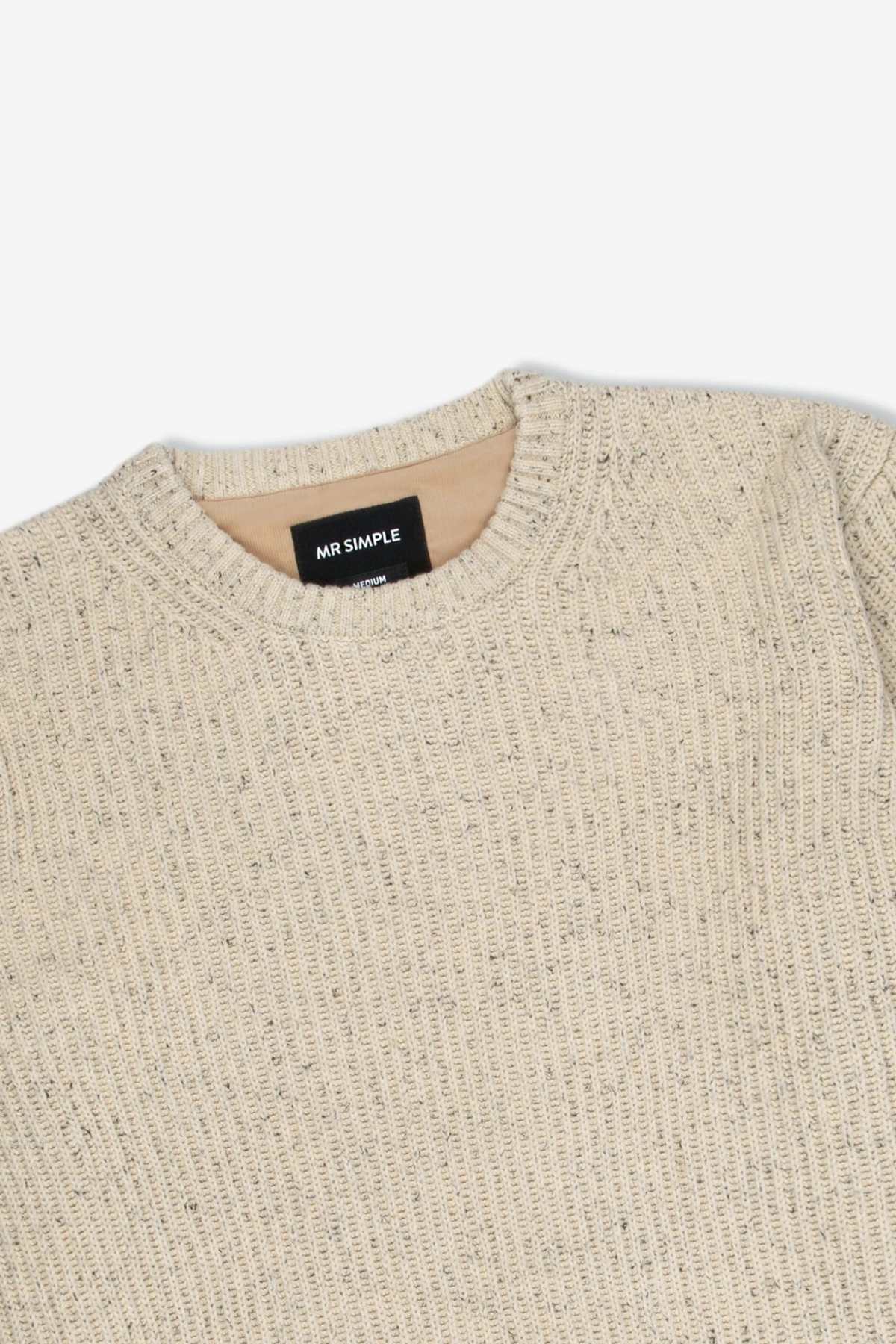 A close-up of the Mr Simple Fisher Knit—a beige organic cotton sweater with ribbed texture, round neckline, and black "MR SIMPLE" tag inside the collar—shows its relaxed fit laid flat on a white background.