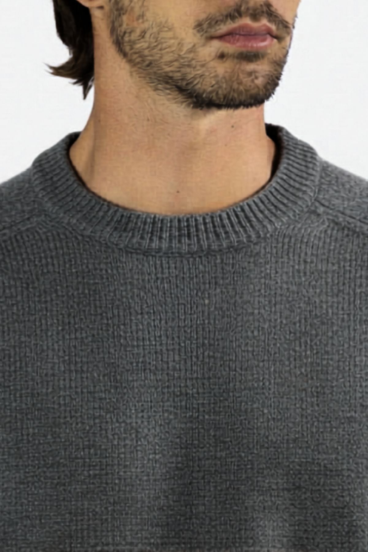A close-up of a person wearing the Mr Simple Fred Knit—a grey, ribbed, 100% wool jumper with a crew neck. Only the lower face, neck, and upper chest are visible against a plain light background. A timeless addition to your winter wardrobe.