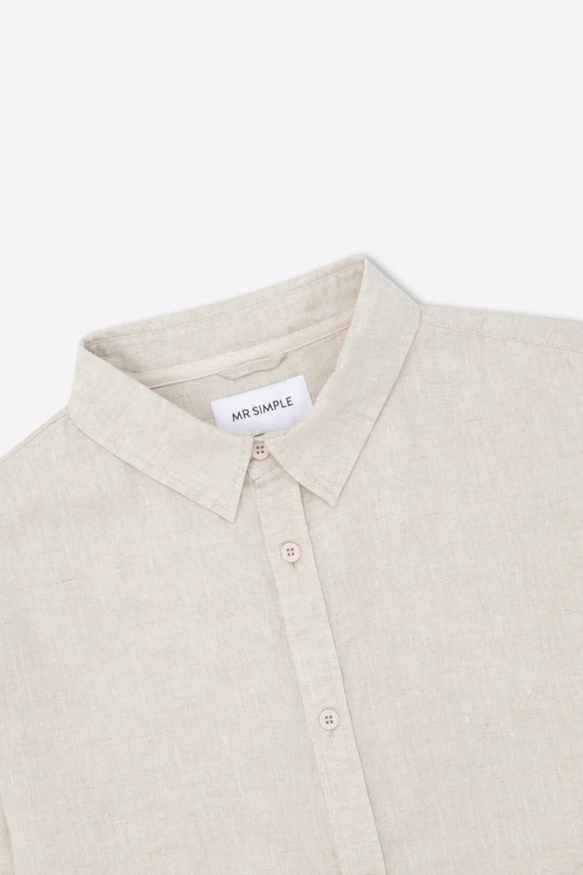 A detailed view of the Mr Simple Linen Long Sleeve Shirt in light beige, showcasing its 100% linen fabric and button-down collar. Stylish details such as a "MR SIMPLE" label sewn into the neckline are highlighted. The lightweight material looks soft and ideal for both casual and semi-formal occasions.